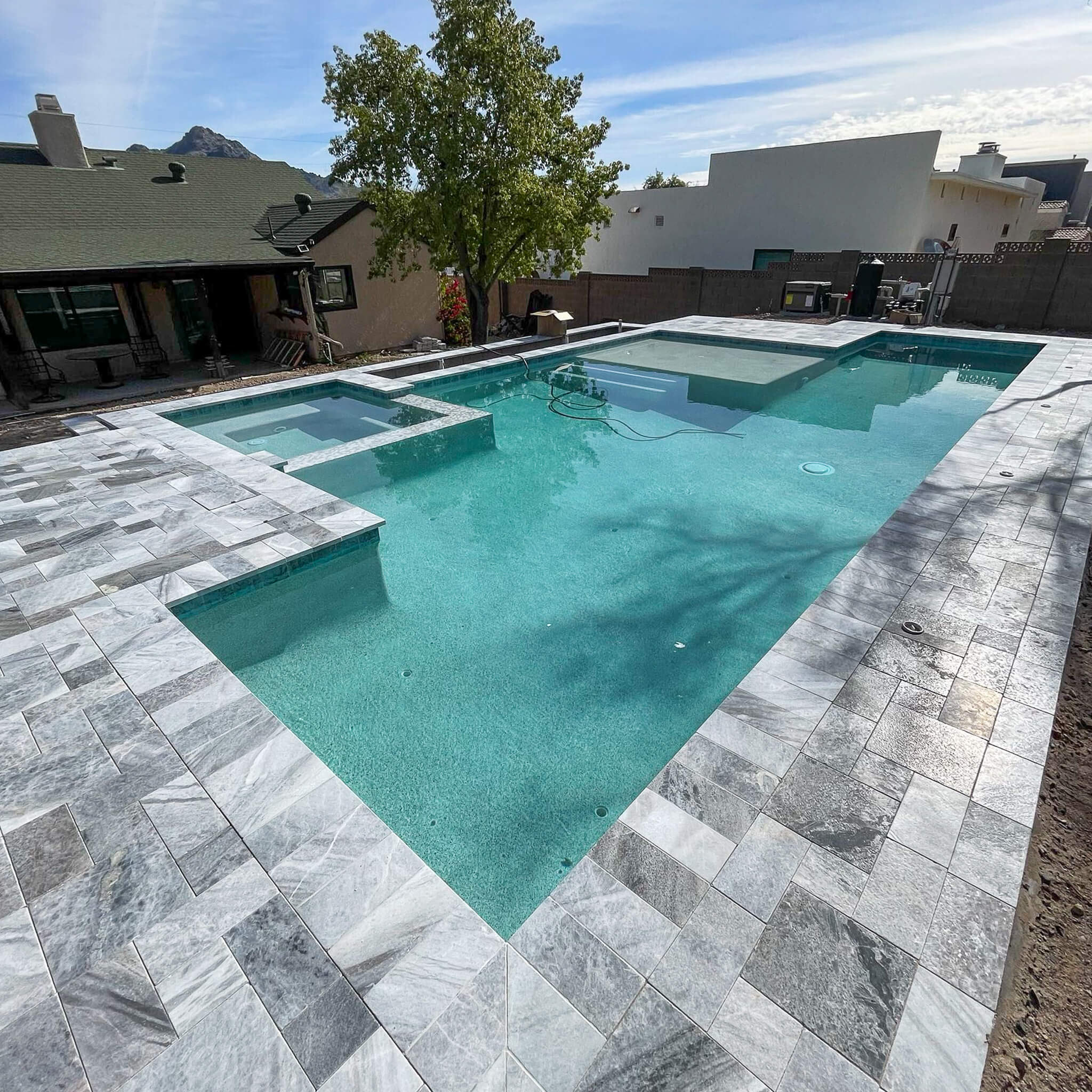 Travertine pool deck with turf and gravel borders in an Arizona backyard